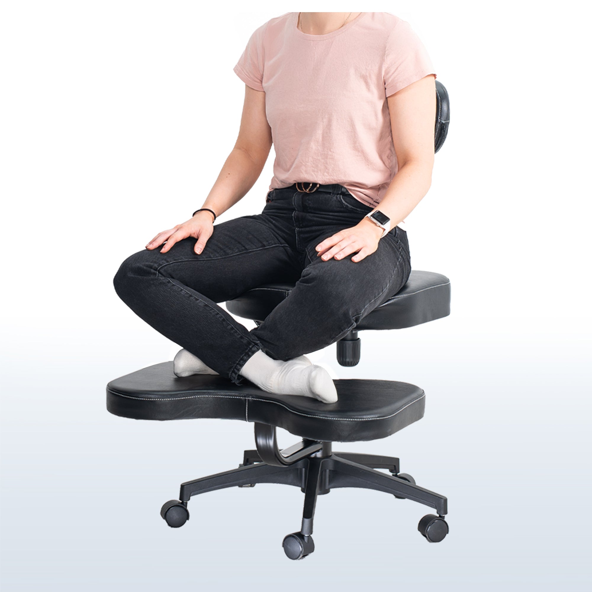 Person sitting on a black kneeling chair with a plain background