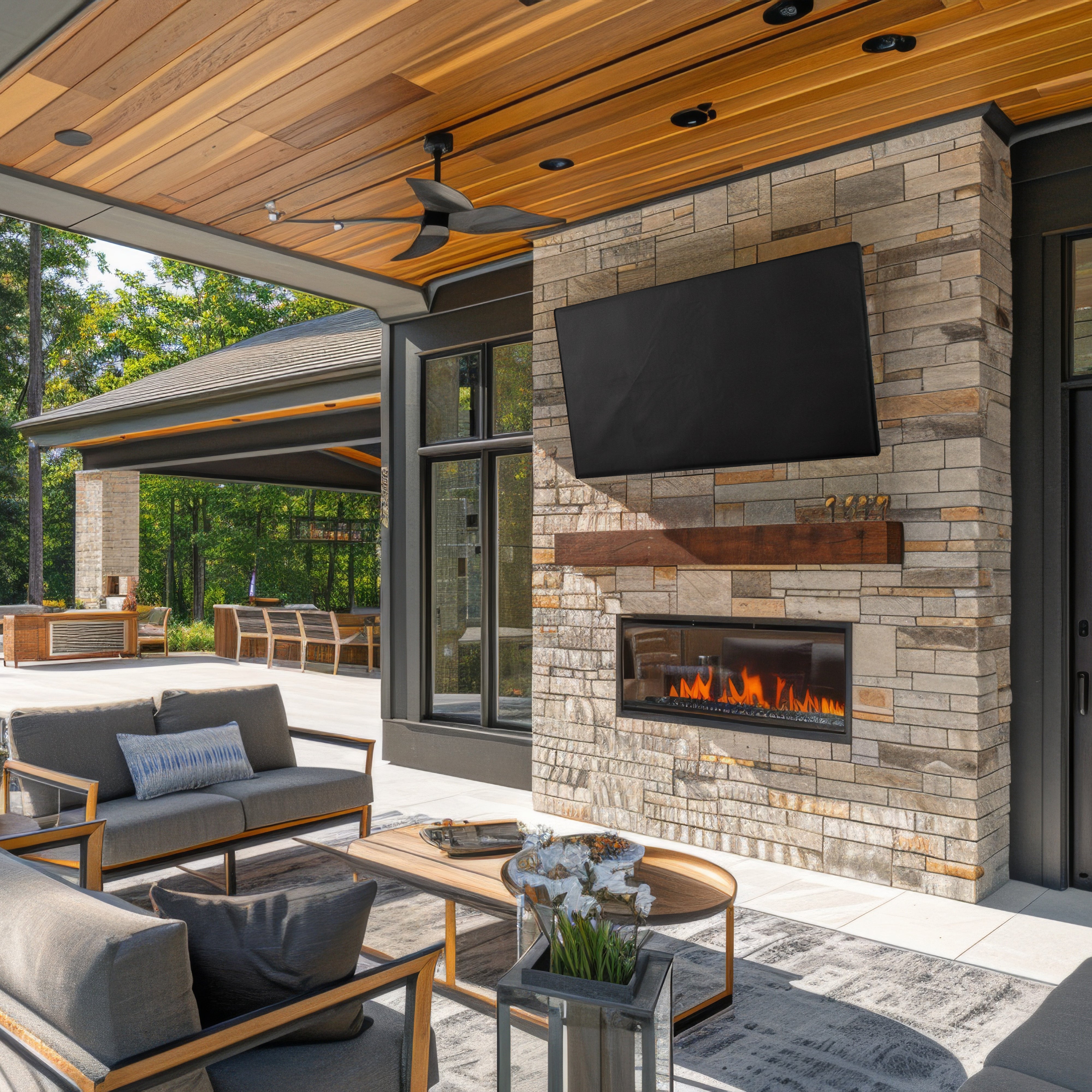 Outdoor patio with stone fireplace, TV and TV cover, and furniture