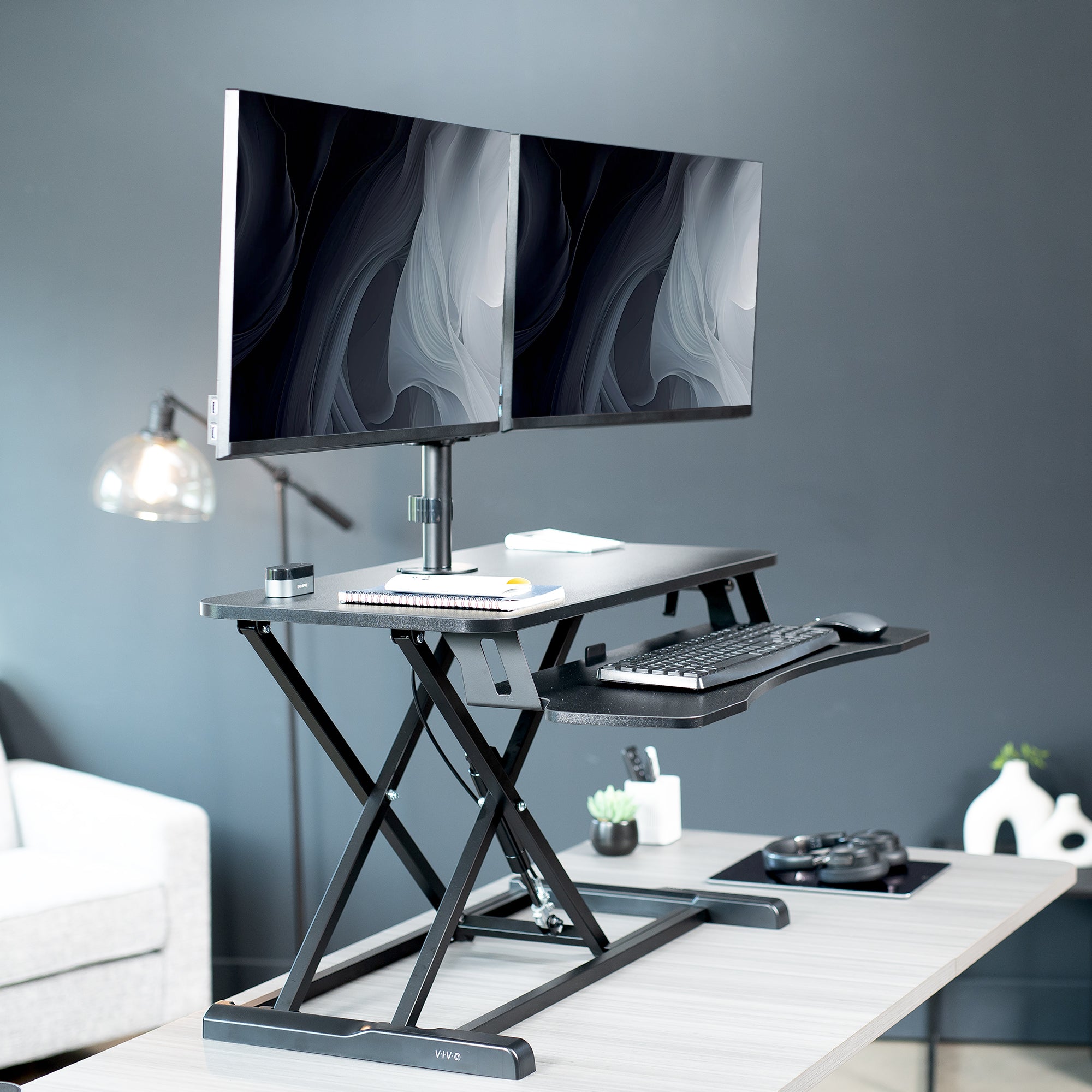 Height adjustable desk riser with articulating mechanical dual monitor mount.