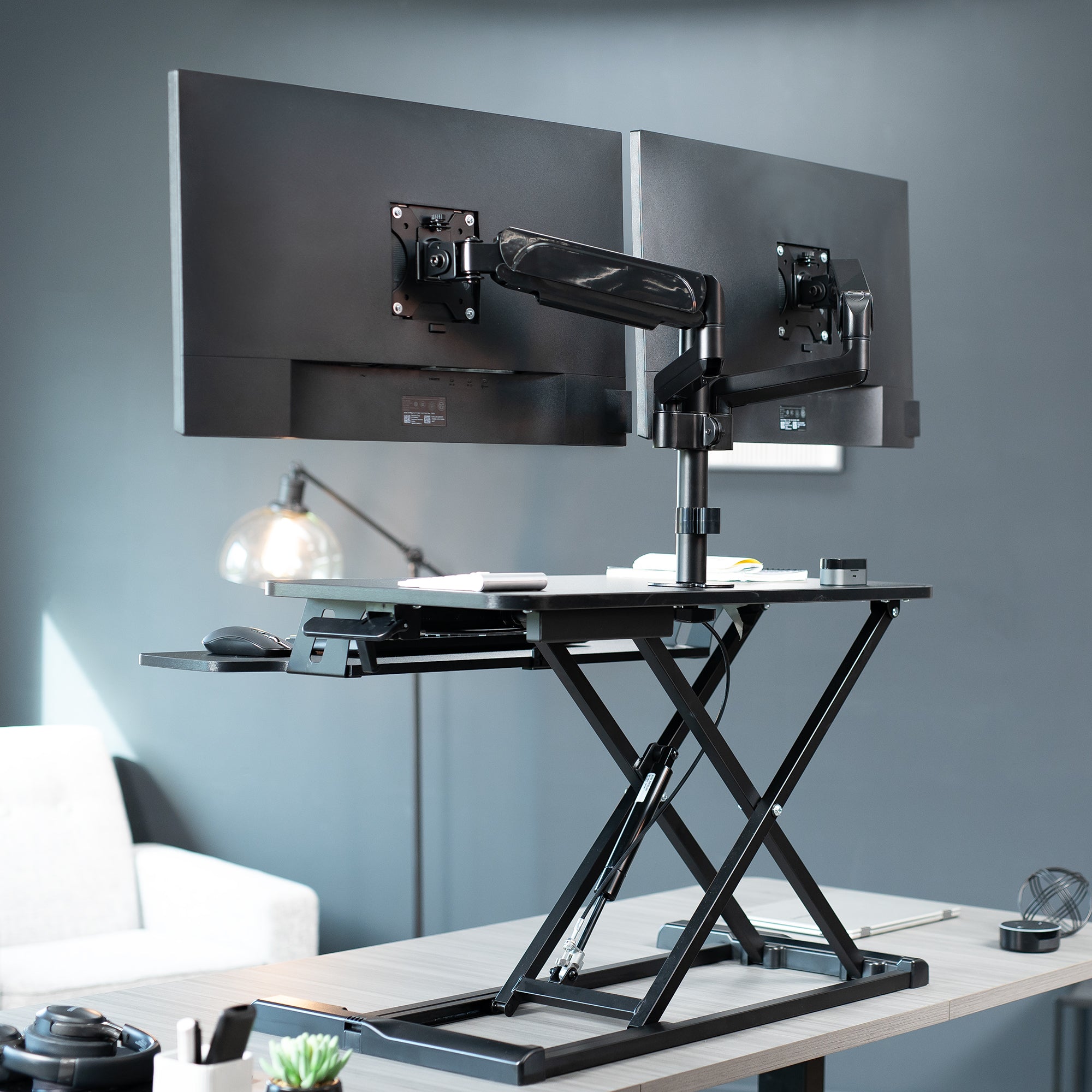 Height adjustable desk riser with articulating mechanical dual monitor mount.