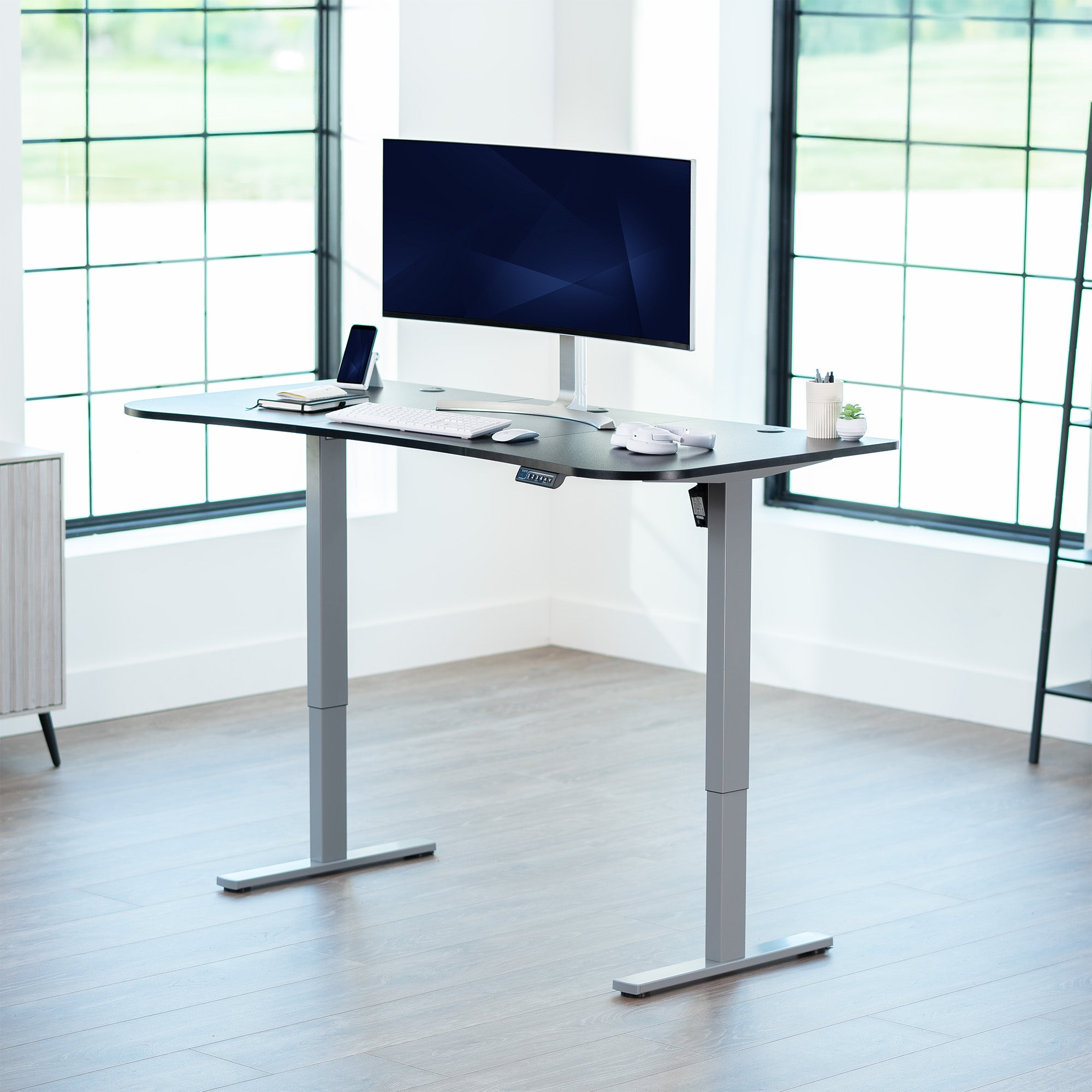 Black top grey frame, electric, sit to stand, height adjustable desk in office setting.