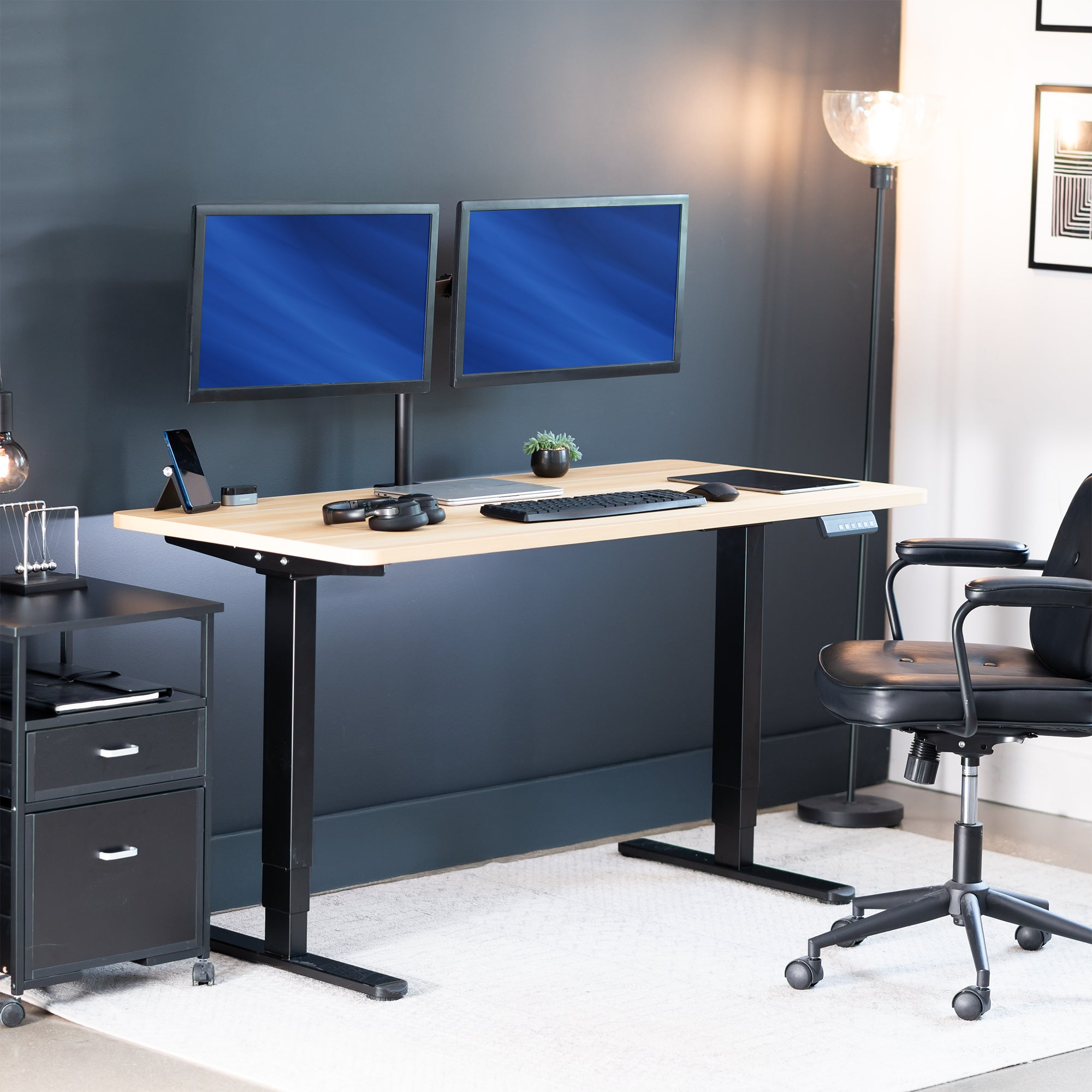 Modern office setup with a standing desk, dual monitors, and office chair.