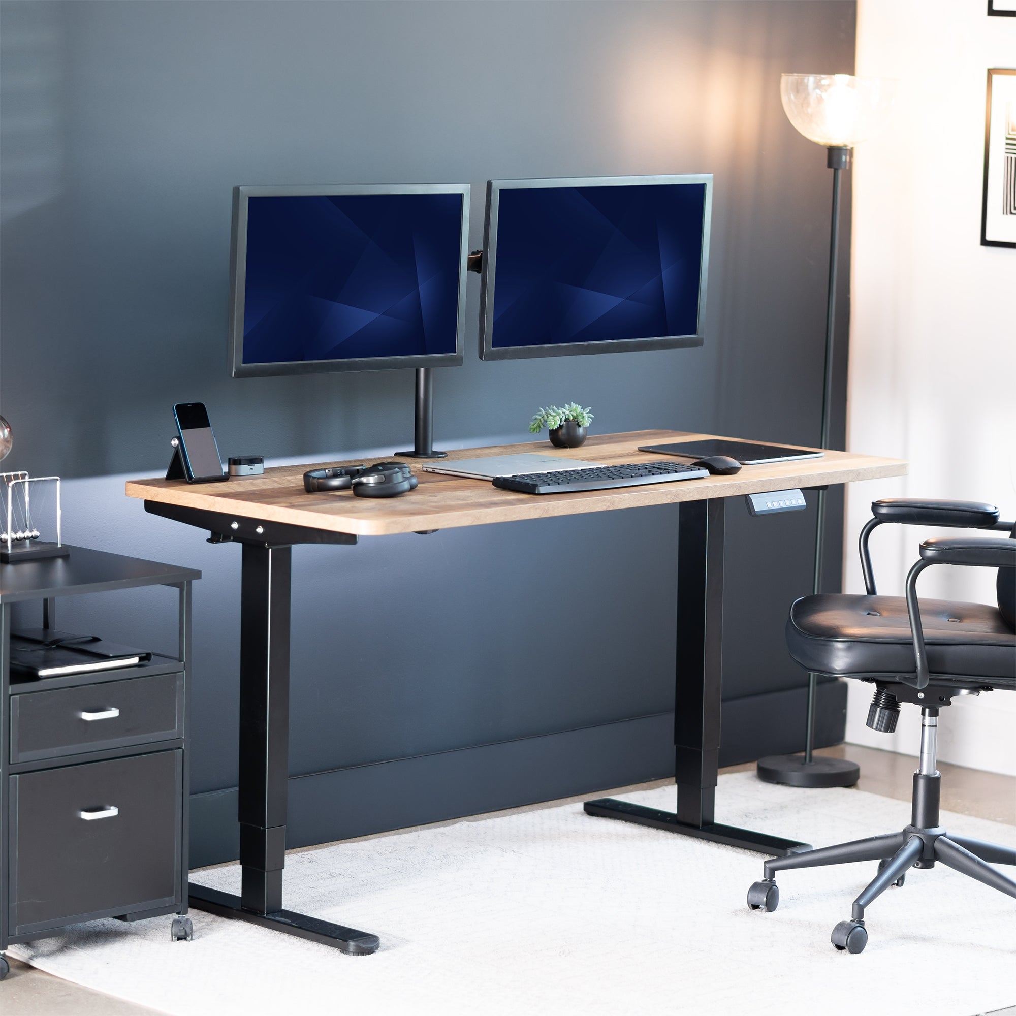 Modern office setup with a standing desk, computer monitors, and office chair.