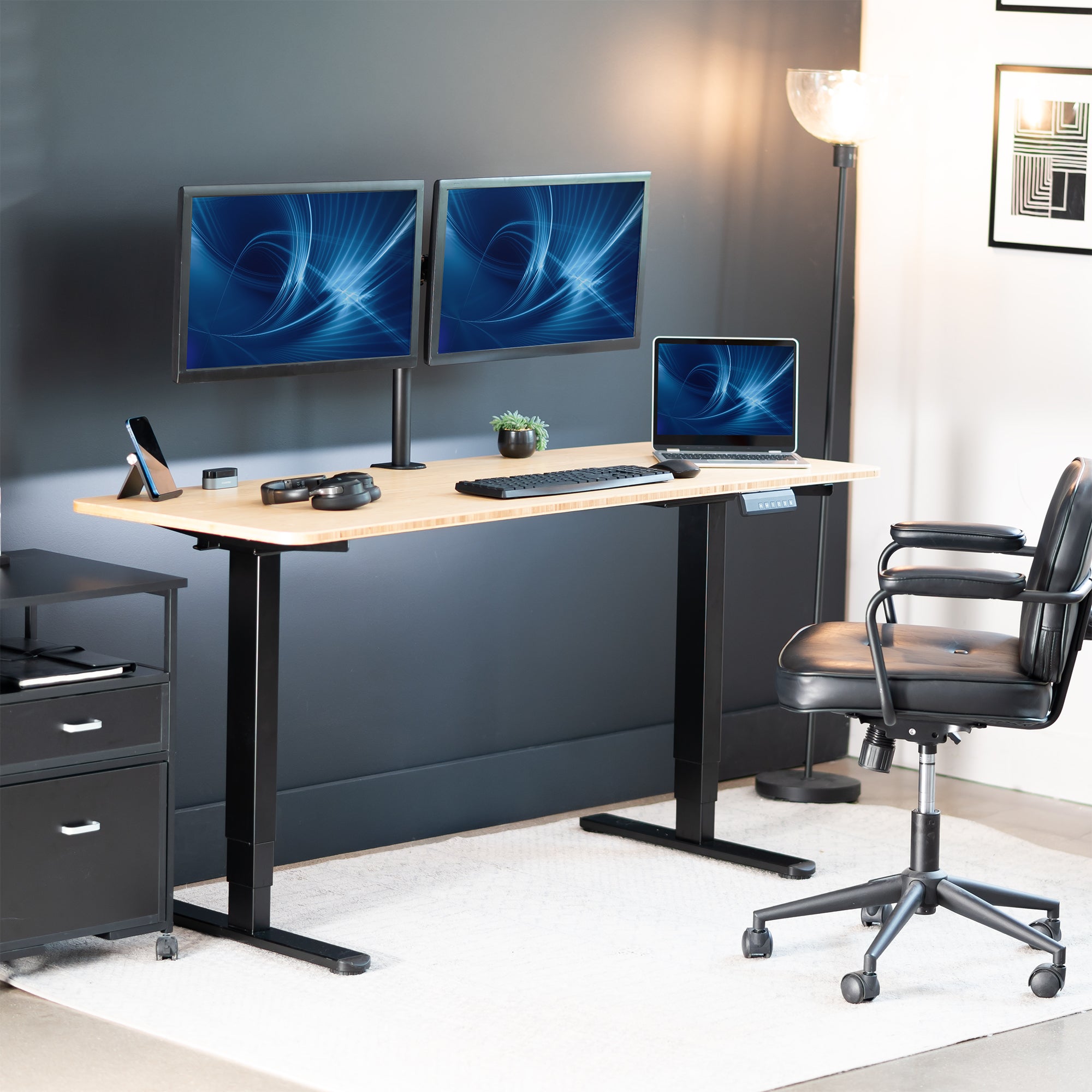 Modern office setup with a standing desk, computer monitors, and a chair.