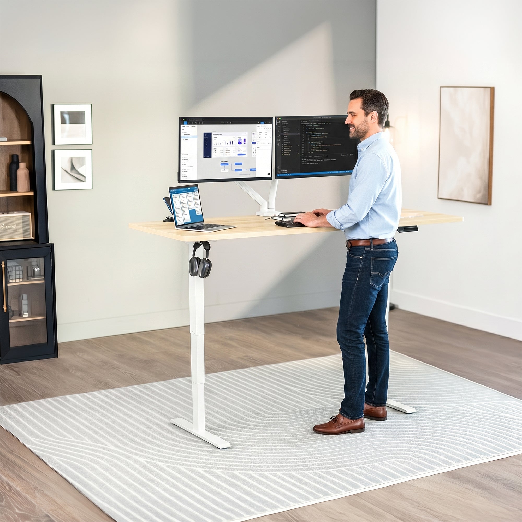 Man standing at an electric height adjustable desktop workstation in office space.
