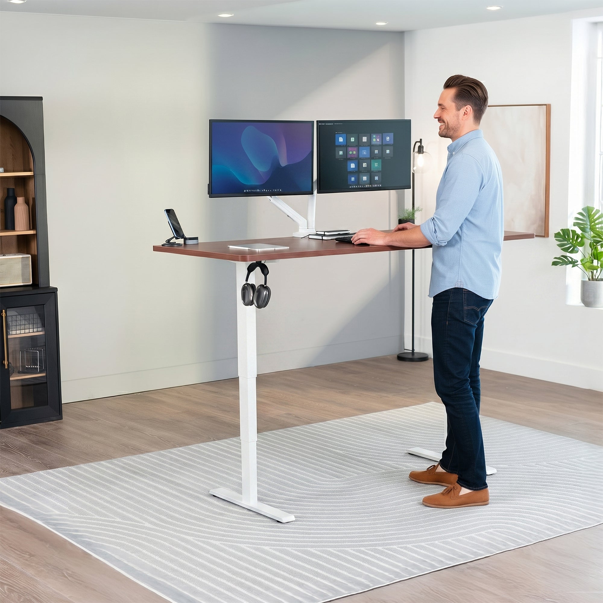 Man standing at an electric height adjustable desktop workstation in office space.