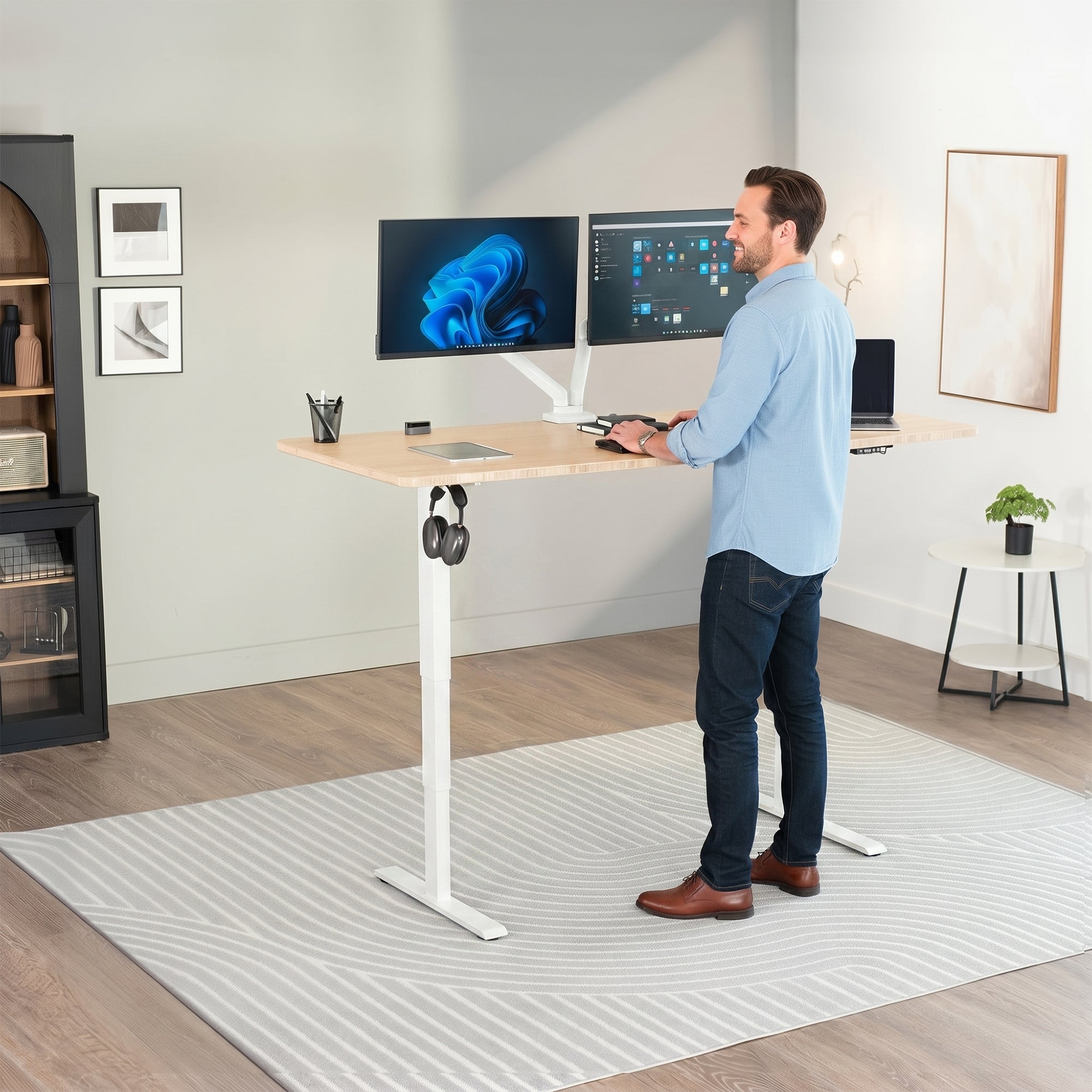 Man standing at an electric height adjustable desktop workstation in office space.