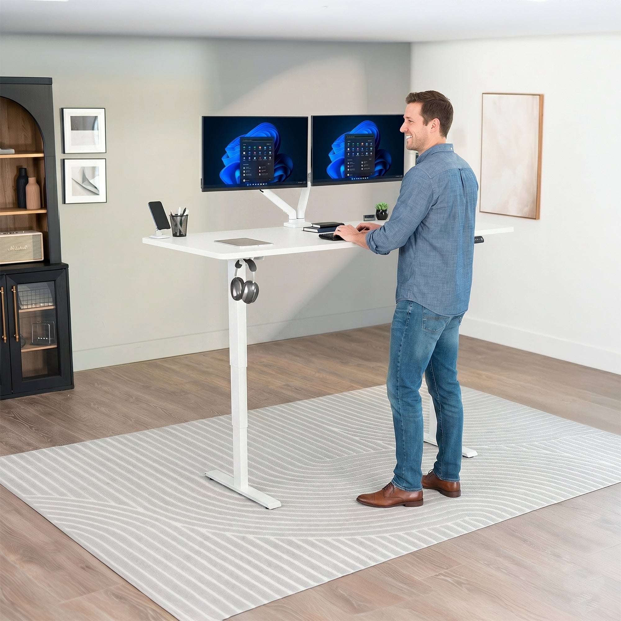 Man standing at an electric height adjustable desktop workstation in office space.