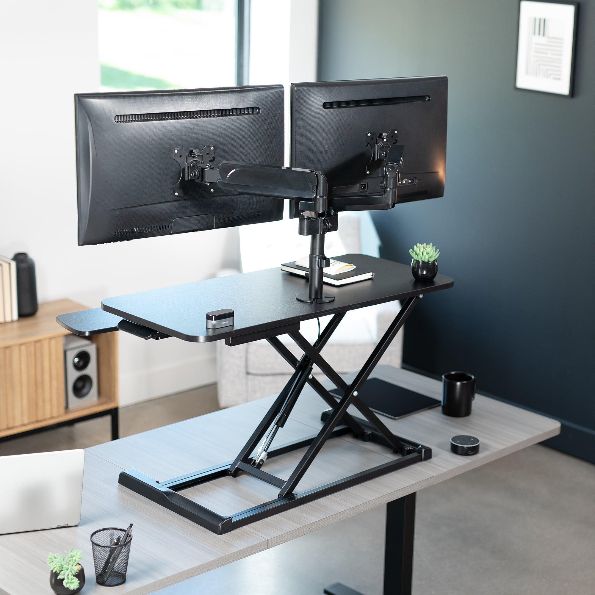 36 inch height adjustable desk riser with articulating mechanical dual monitor mount.