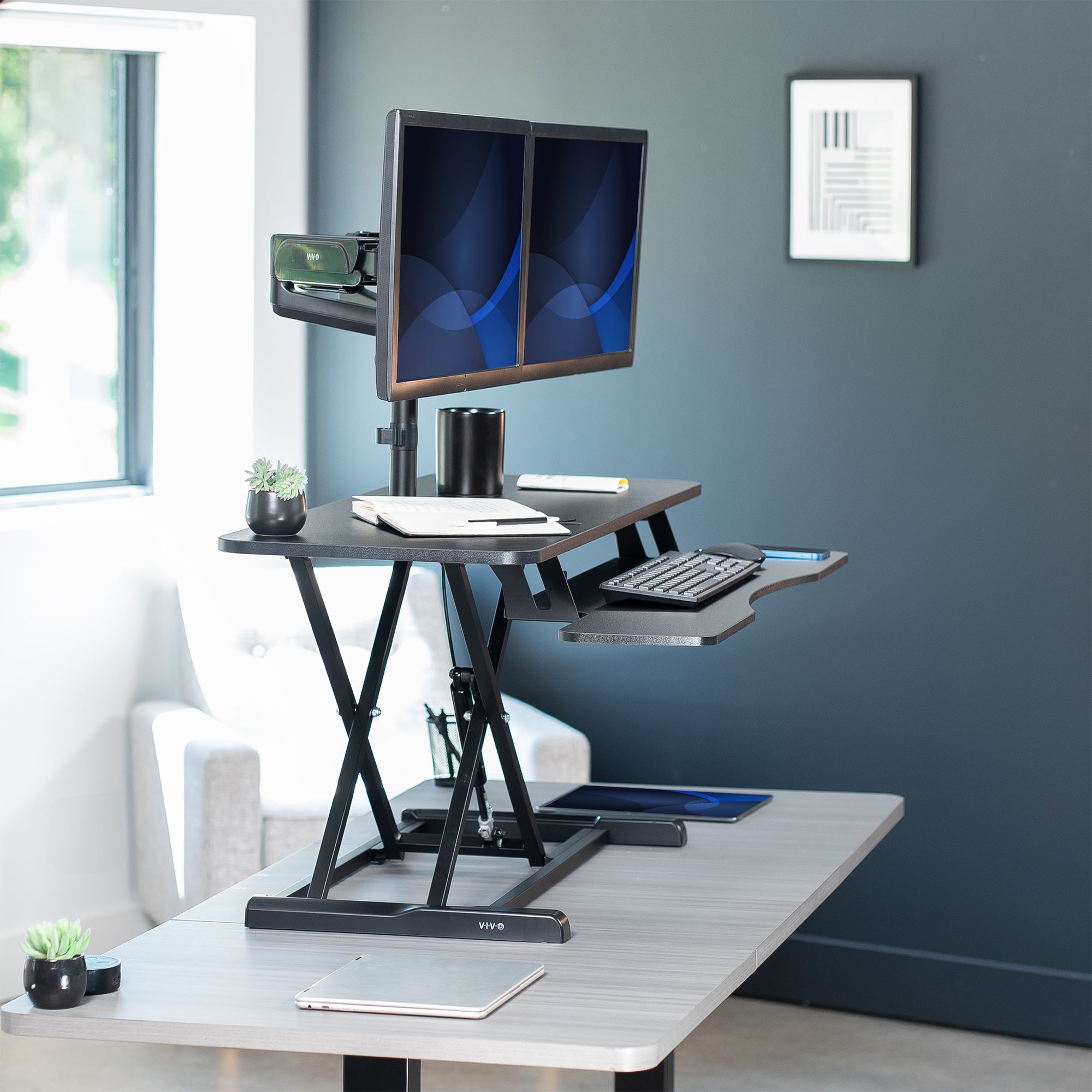 42 inch height adjustable desk riser with articulating mechanical dual monitor mount.