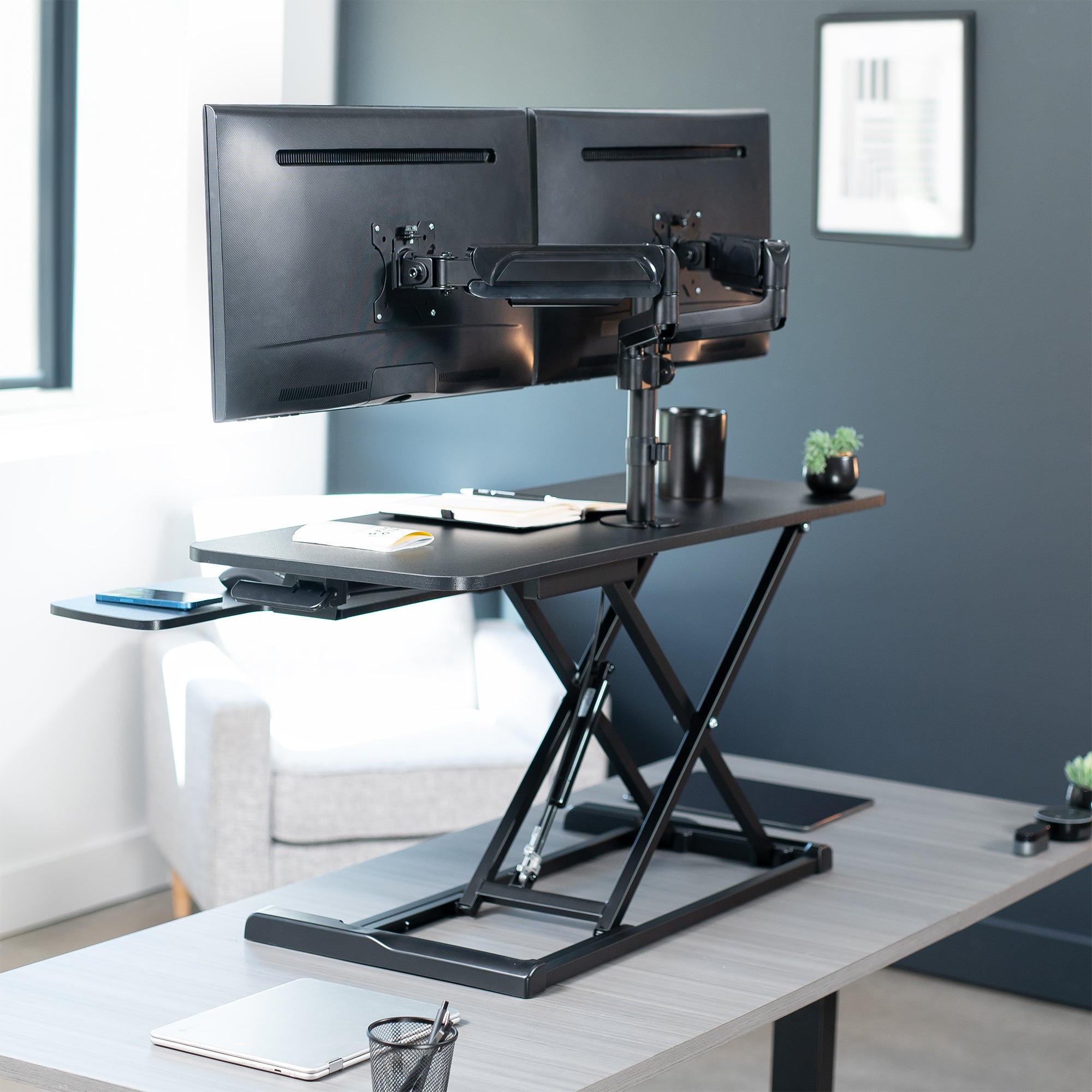 42 inch height adjustable desk riser with articulating mechanical dual monitor mount.
