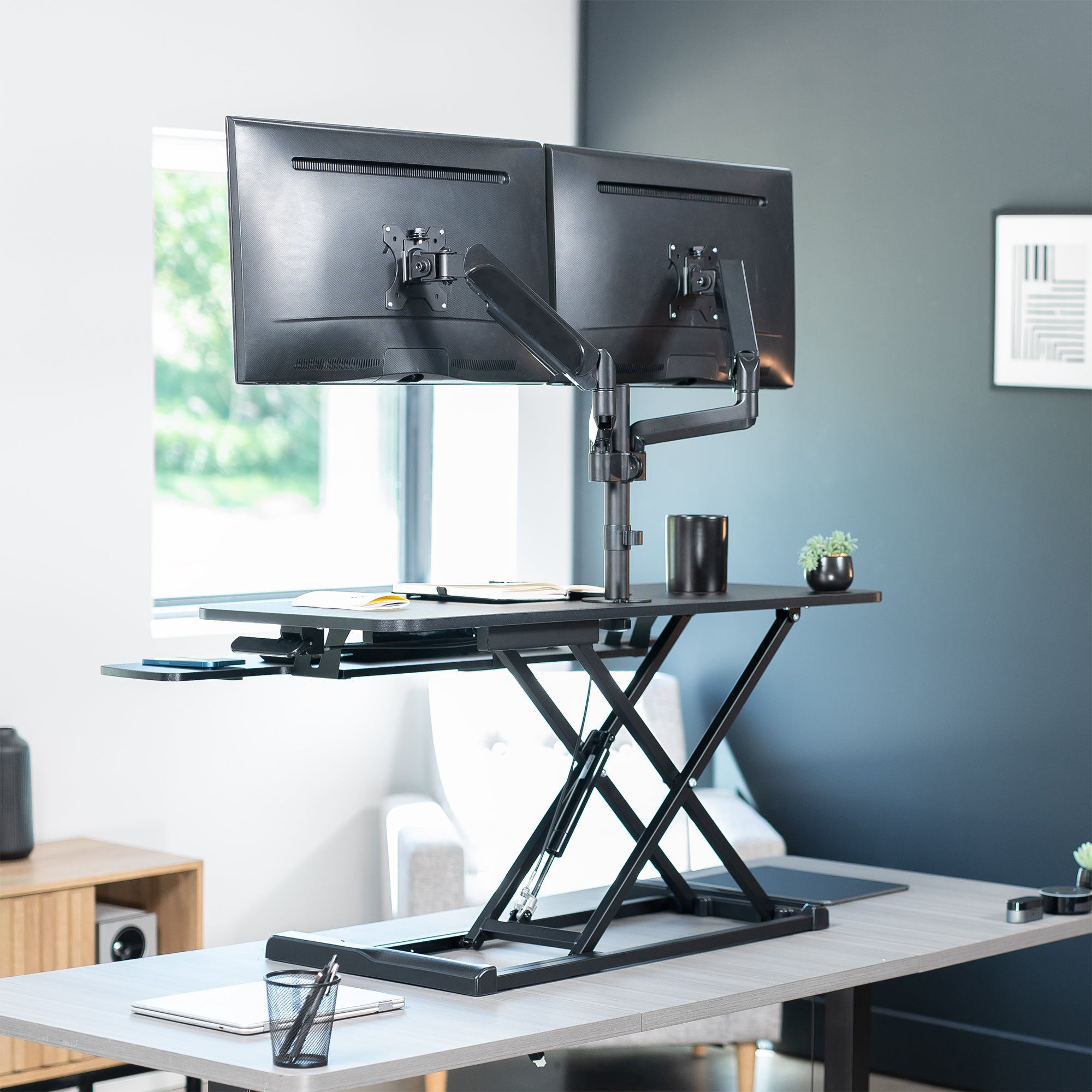 42 inch height adjustable desk riser with articulating mechanical dual monitor mount.