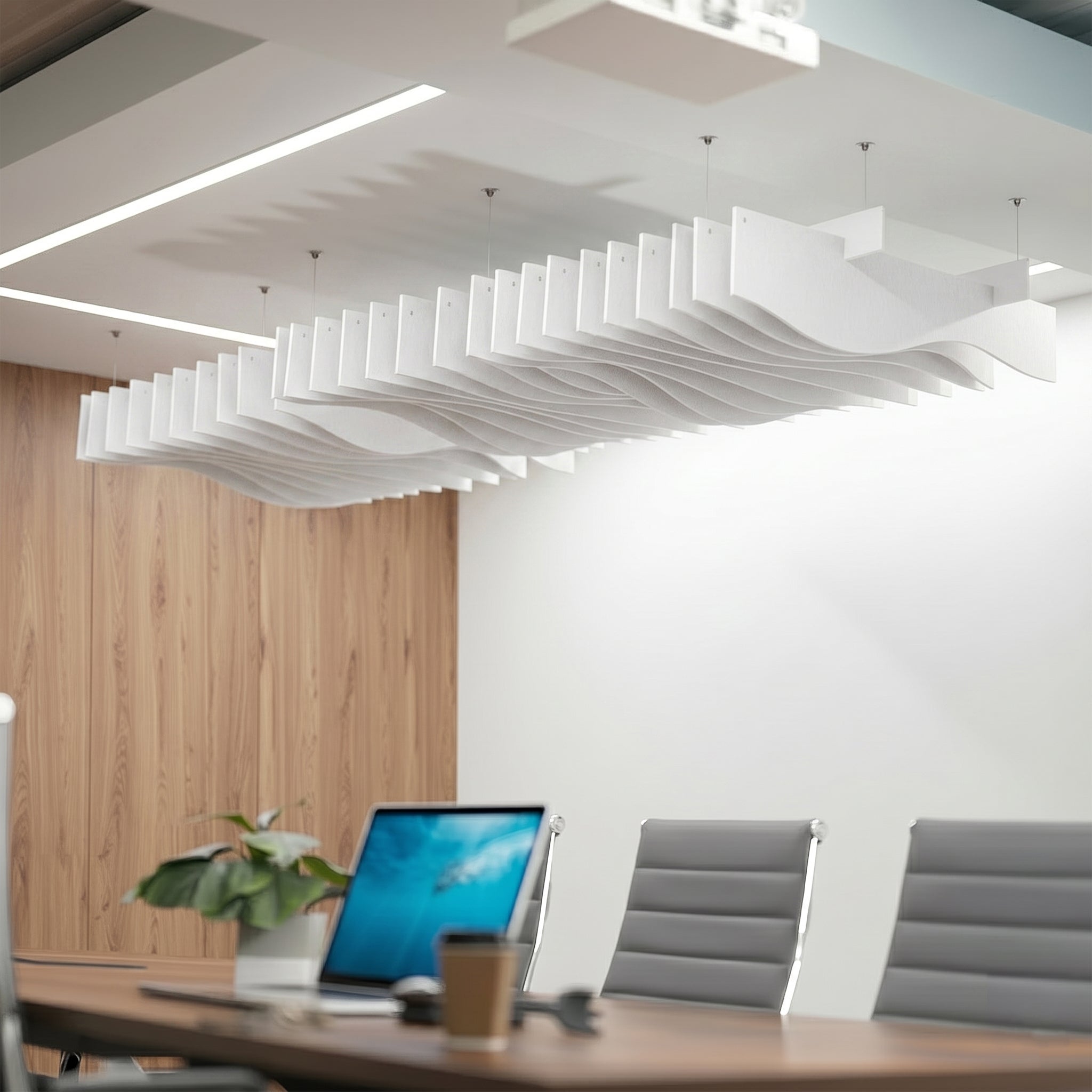 A modern office interior with a large wavy, layered white acoustic ceiling fixture suspended over a conference table.