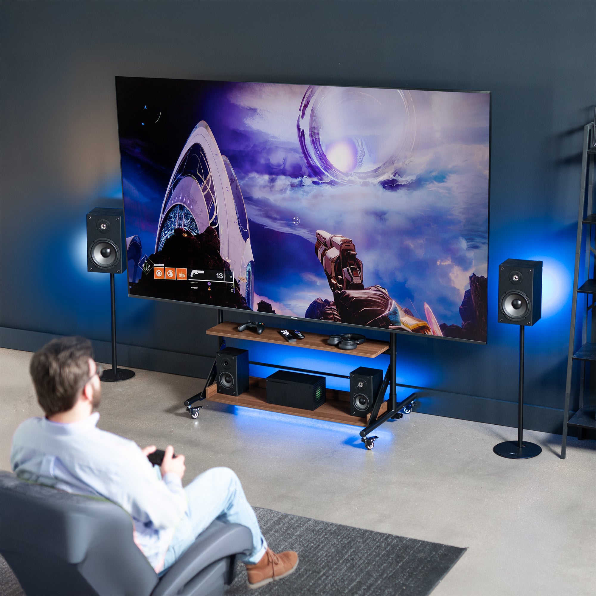 A heavy duty TV cart with dark wood shelves with a man watching a sci-fi movie on the screen.