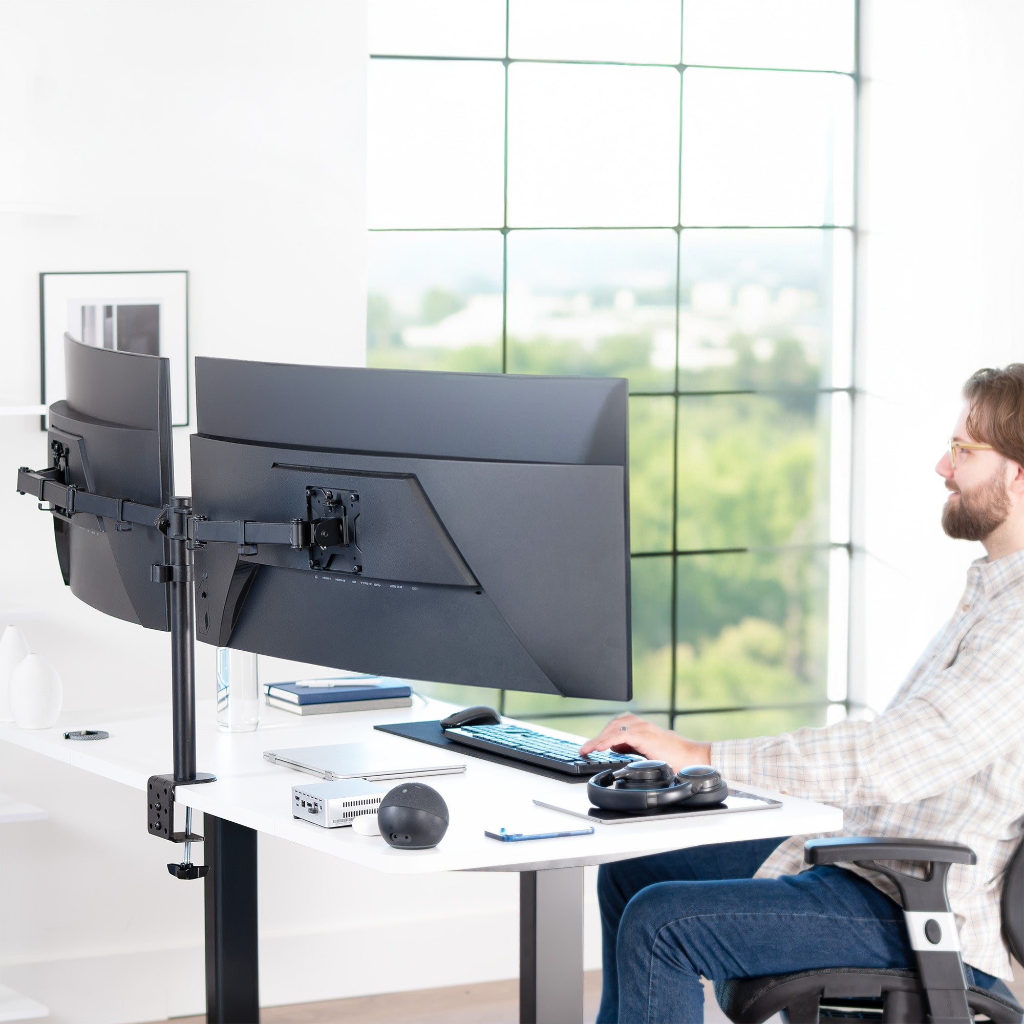 Person sitting at a desk with a dual monitor setup in an office setting.