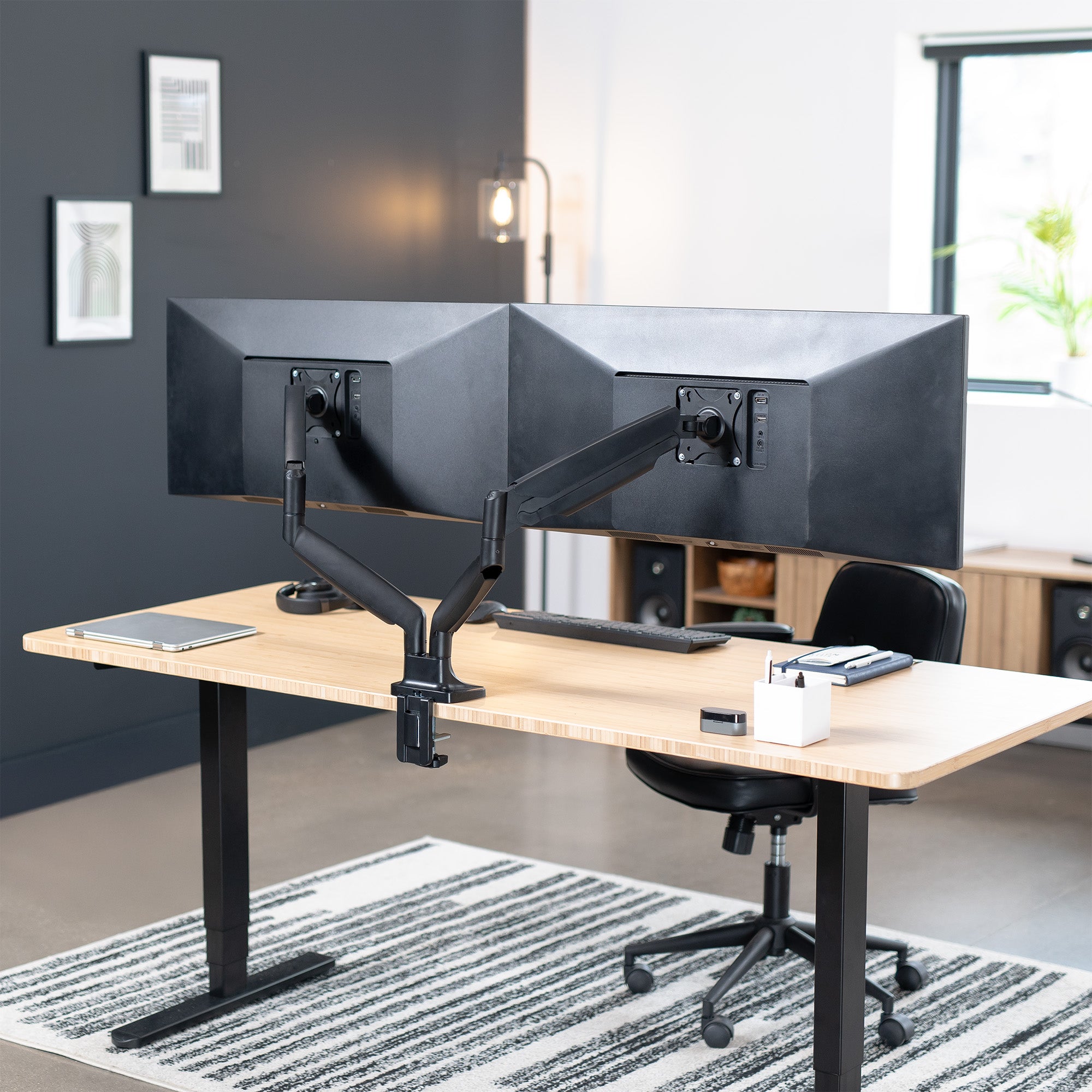 A dual ultrawide monitor desk mount with pneumatic arms in a modern office setting.