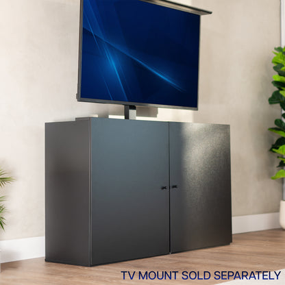 Black TV cabinet with a concealed television displaying a blue screen, on a wooden floor with a plant in the background.