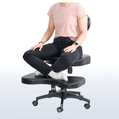 Person sitting on a black kneeling chair with a plain background