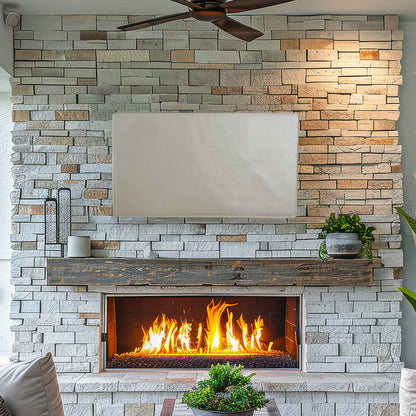 Protective flat screen TV cover on TV mounted above fireplace with stone wall background.