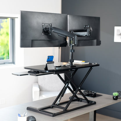 36 inch height adjustable desk riser with articulating mechanical dual monitor mount.