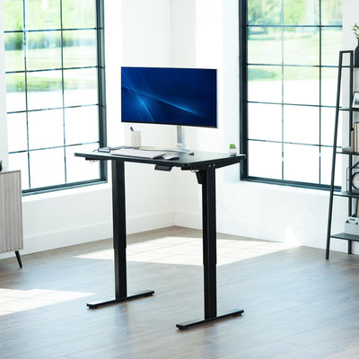 Black, height adjustable, electric, sit to stand desk in office setting. 