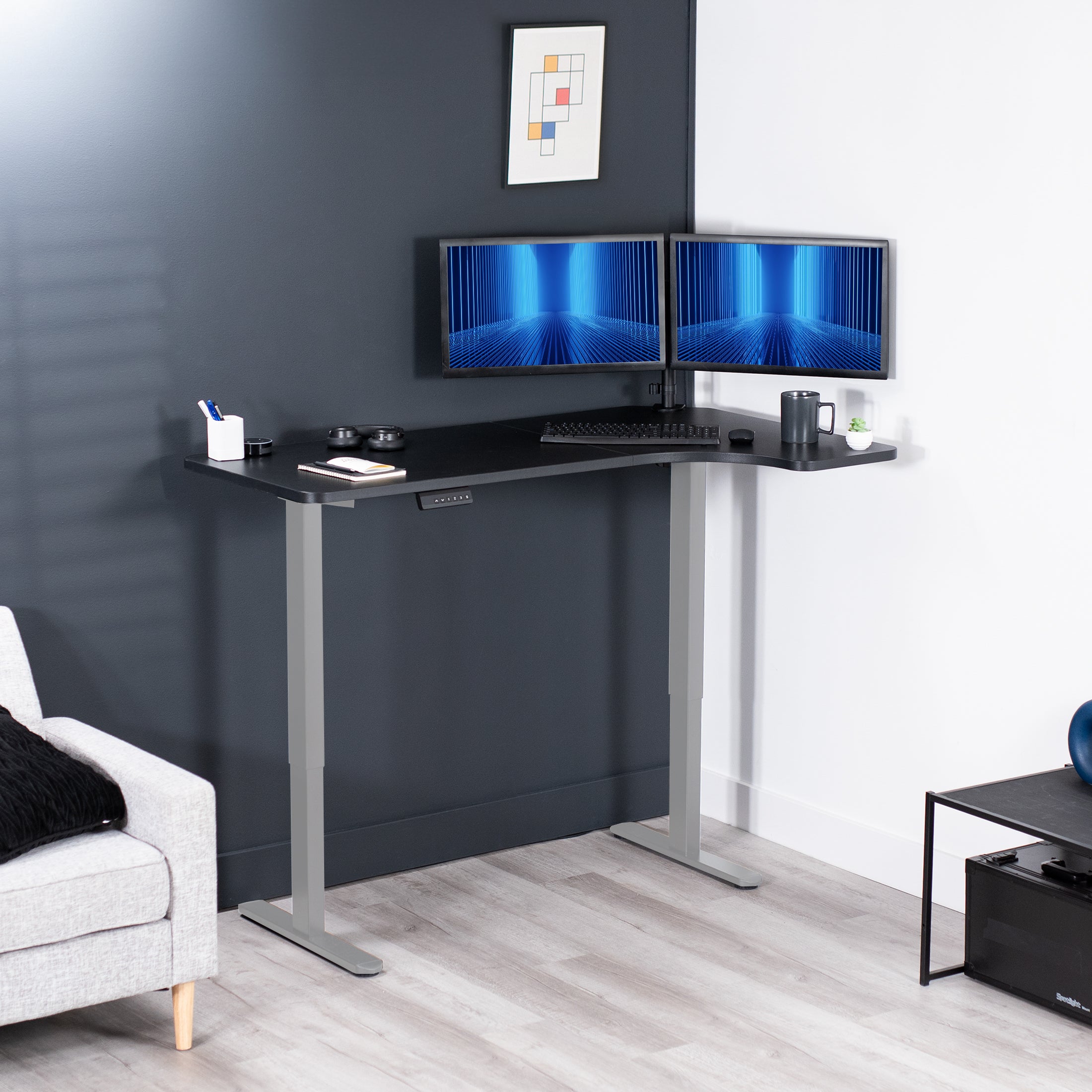 Dual monitor mount attached to a height adjustable desk with a slight corner curve offering more workspace to the side of choice.