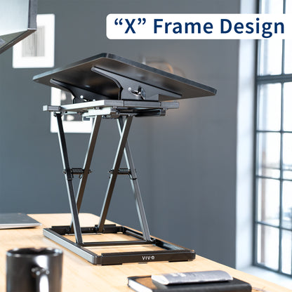 A black tilting keyboard riser with an "X-frame" design. 