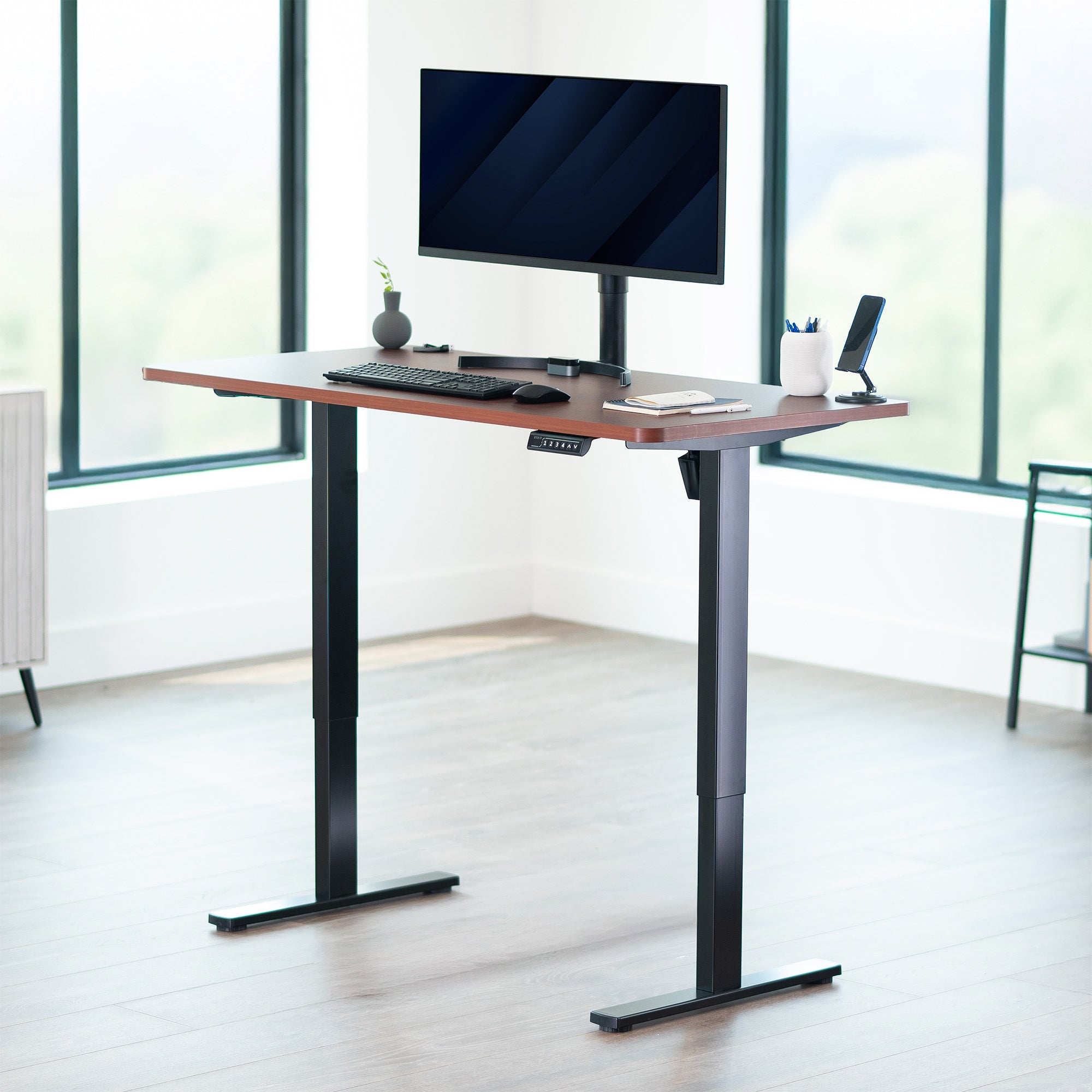Adjustable height desk with computer setup in a bright room