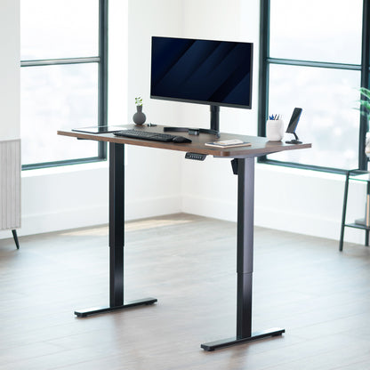 Modern adjustable desk with computer setup in a bright room