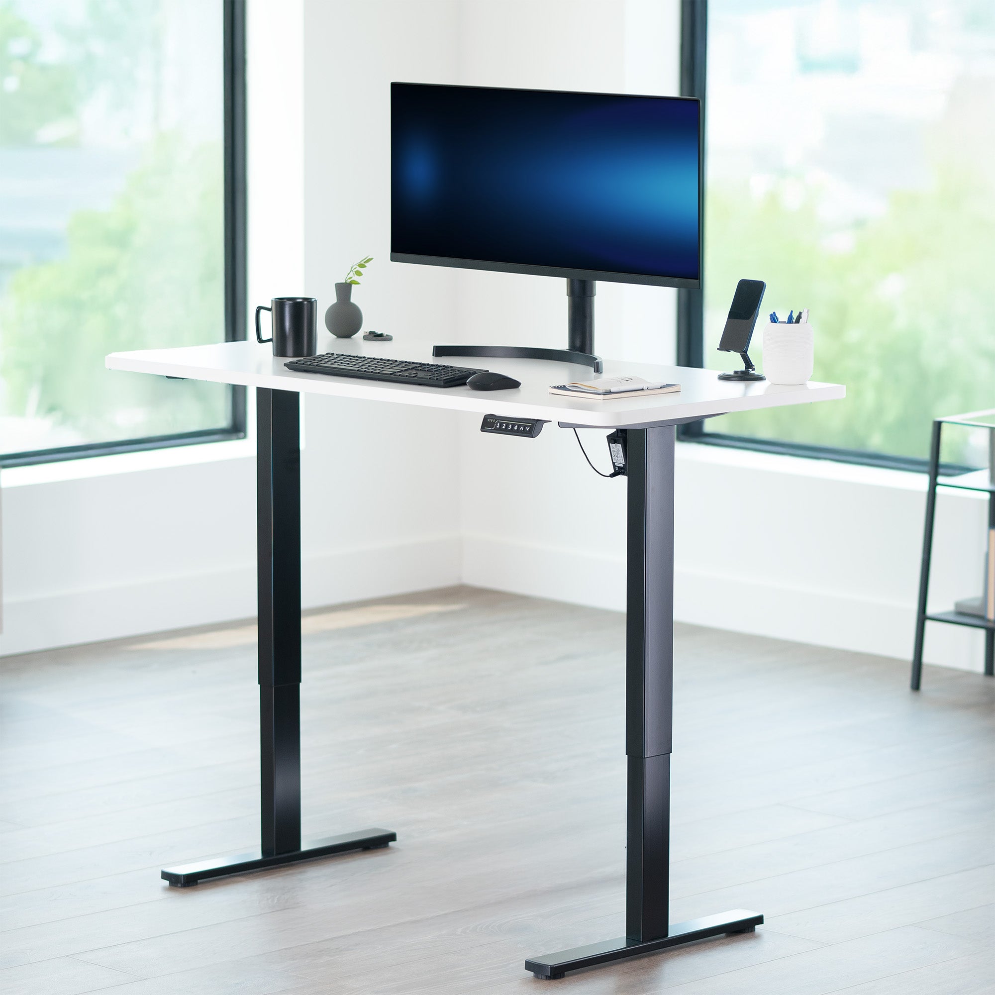 Adjustable height desk with computer setup in a bright room