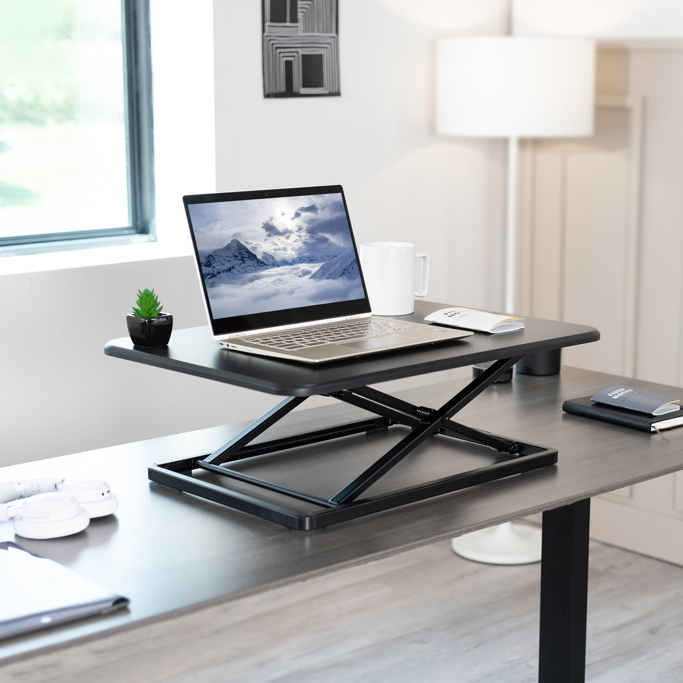 Extending desk riser supporting a laptop and other desk accessories.