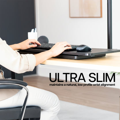 Person using a computer with an ultra slim keyboard on a desk, emphasizing comfort and design.