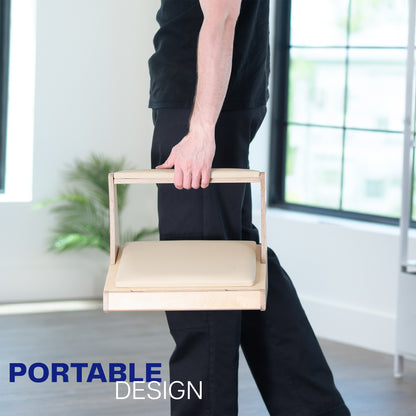Person holding a portable wooden footrest in a minimalistic room.