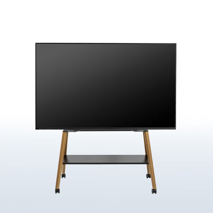 A large flat-screen display monitor on a wheeled easel TV stand with a black screen, slim black frame, and light wood legs, shown against a light gray gradient background.