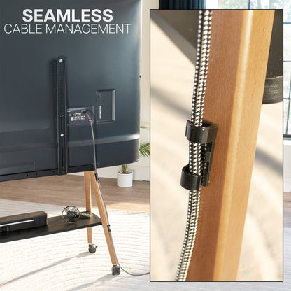 A cable management clip holding a braided black and silver cable next to a wooden furniture frame, with a TV stand and TV in a room shown in the background and the text 'SEAMLESS CABLE MANAGEMENT' at the top.