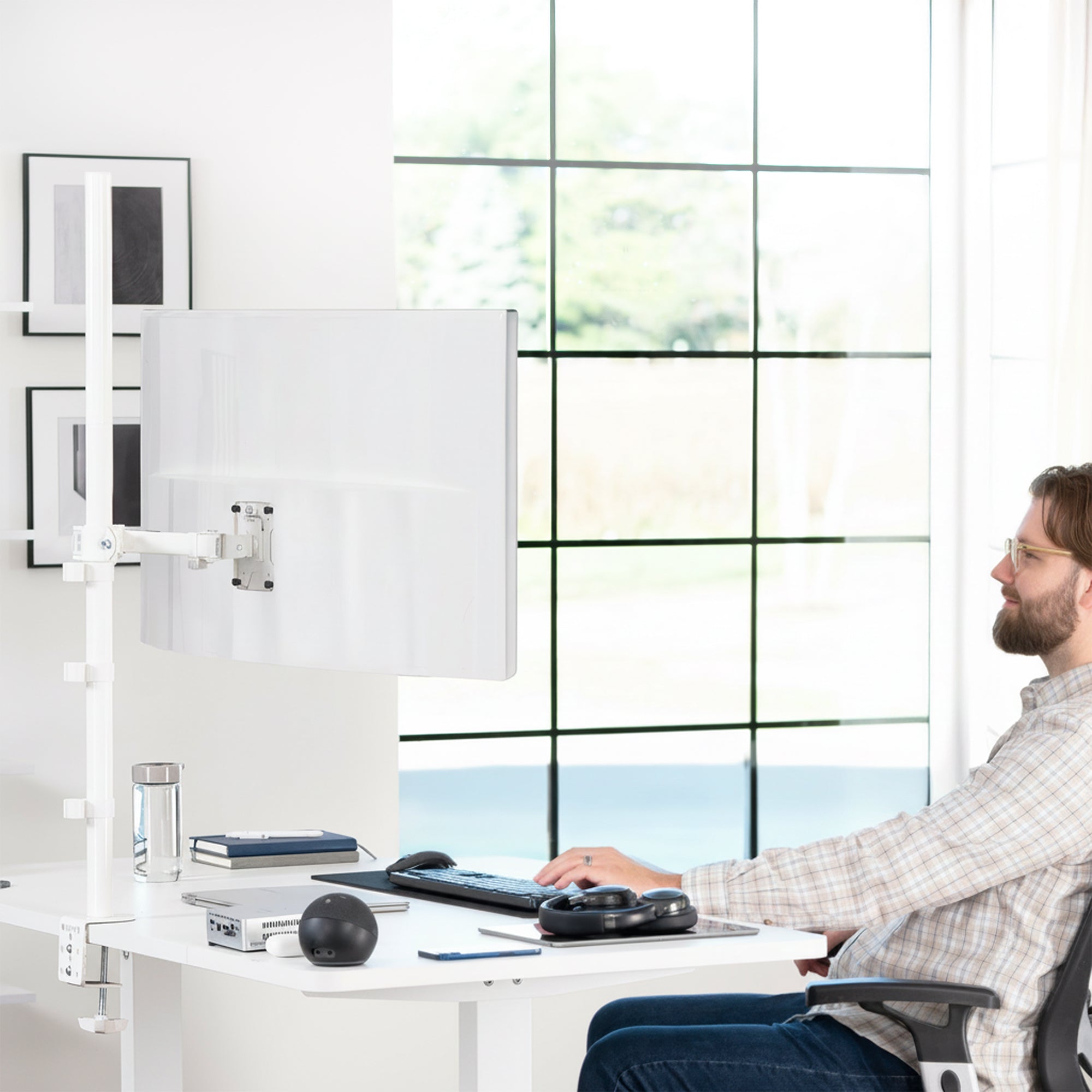 Person using a computer setup with a monitor on an adjustable extra tall monitor stand in a modern office.