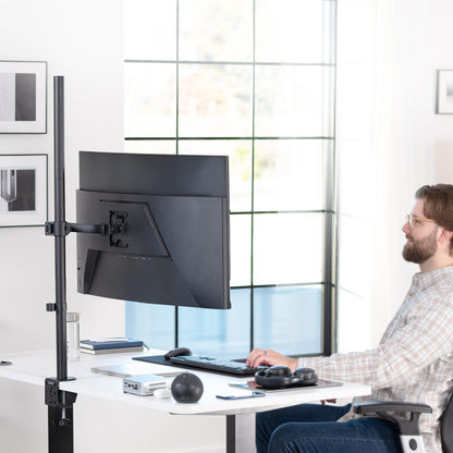 Person using a computer setup with a monitor on an adjustable extra tall monitor stand in a modern office.