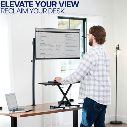 Man using a standing keyboard desk riser and extra tall monitor stand in a home office setting with text 'Elevate Your View, Reclaim Your Desk'.