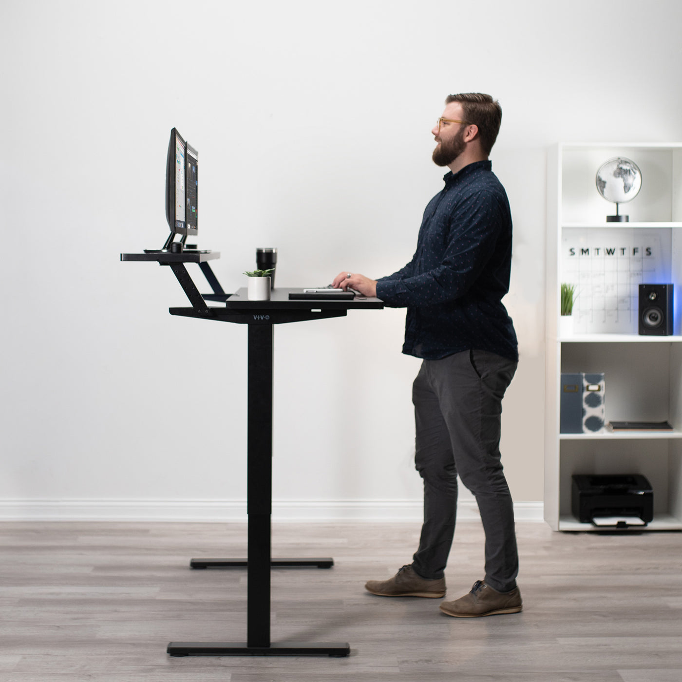A man working at the split-top, sit-to-stand desk.