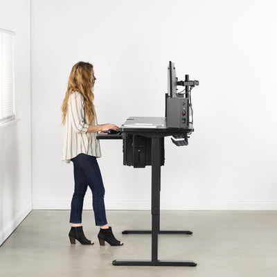 Woman working from a comfortable and ergonomic standing height at an electric desk.