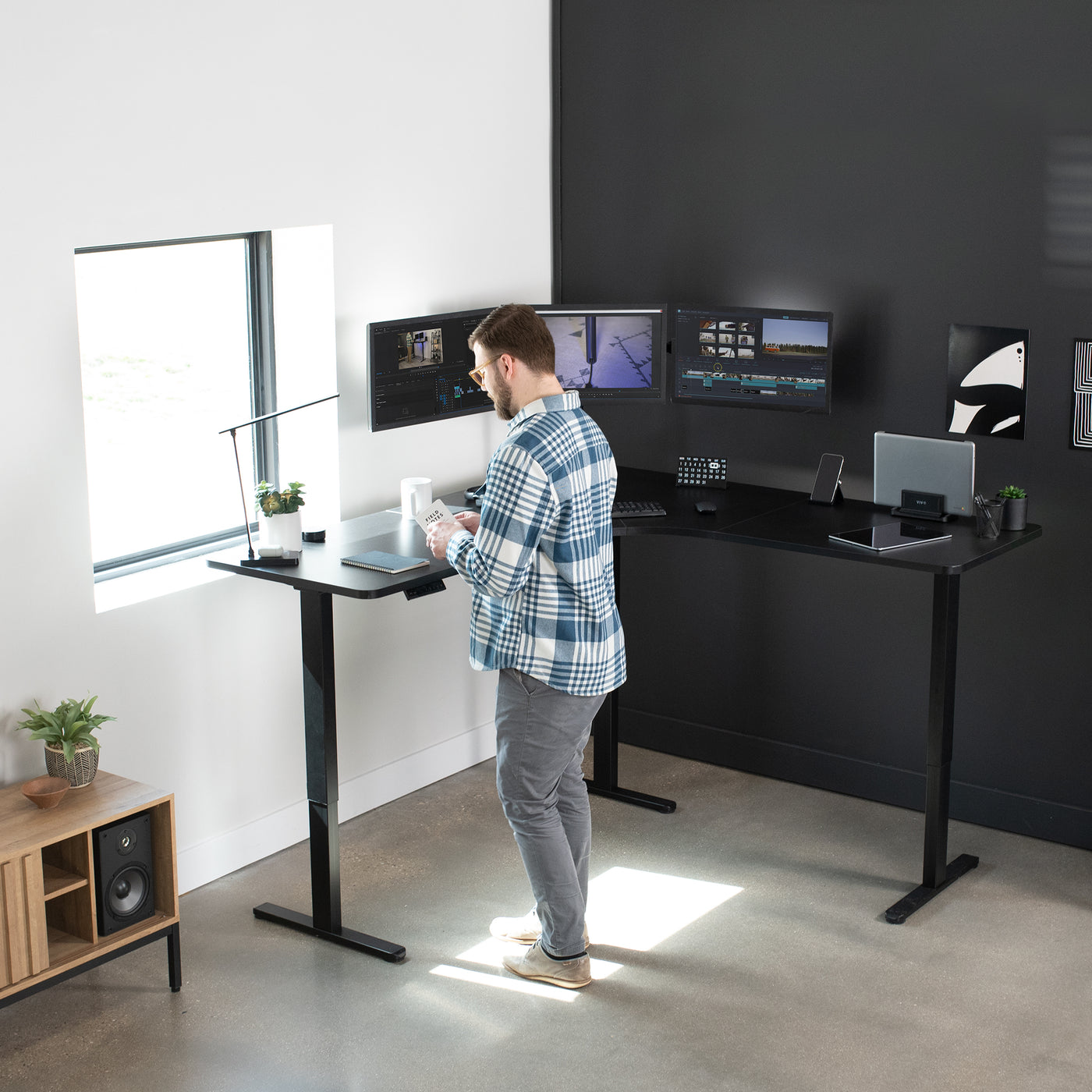 Man working at L-shaped standing desk aligned with the corner walls of an office room.