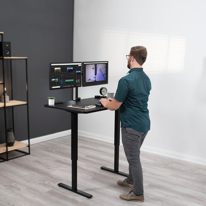 A man working at an ergonomic height adjustable standing desk.