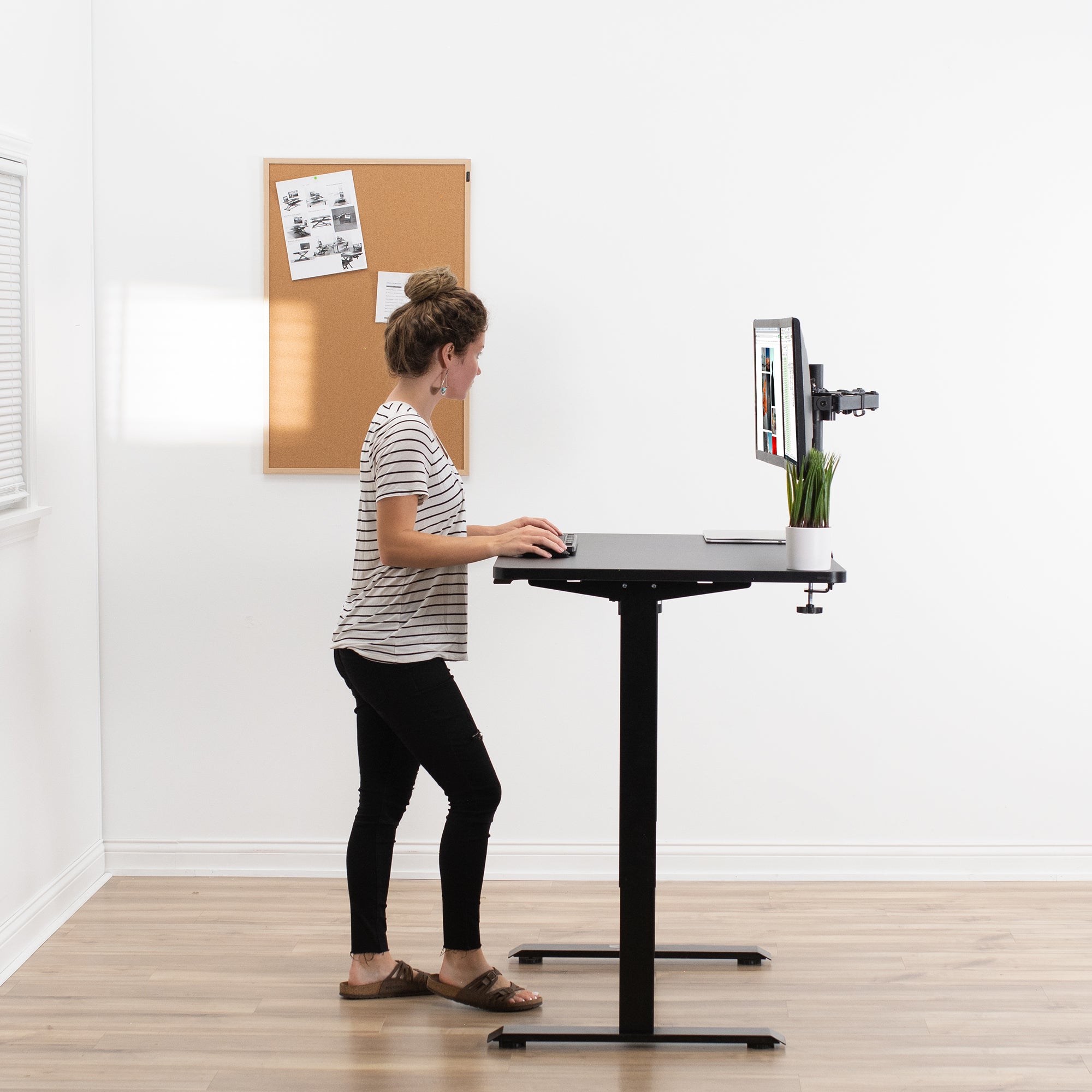 Woman working at a sit-to-stand desk with a medium-sized desktop from VIVO.