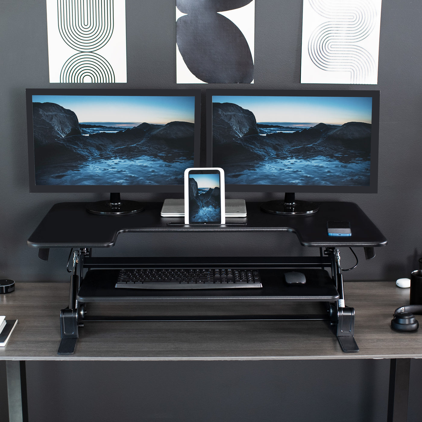Desk converter in use with two monitors with device propped up in designated device holder slot.