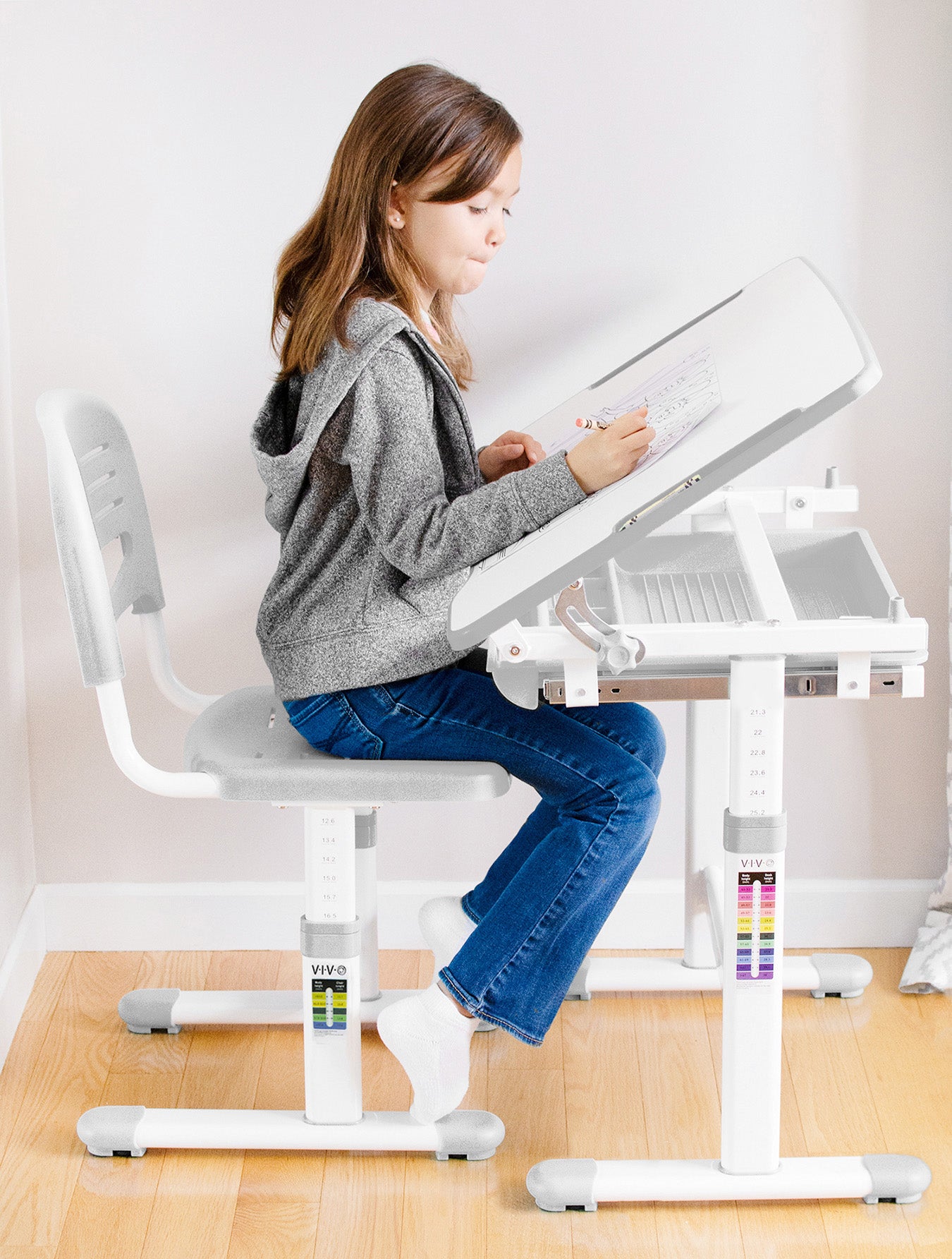 A girl working at a height-adjustable ergonomic kids' desk.