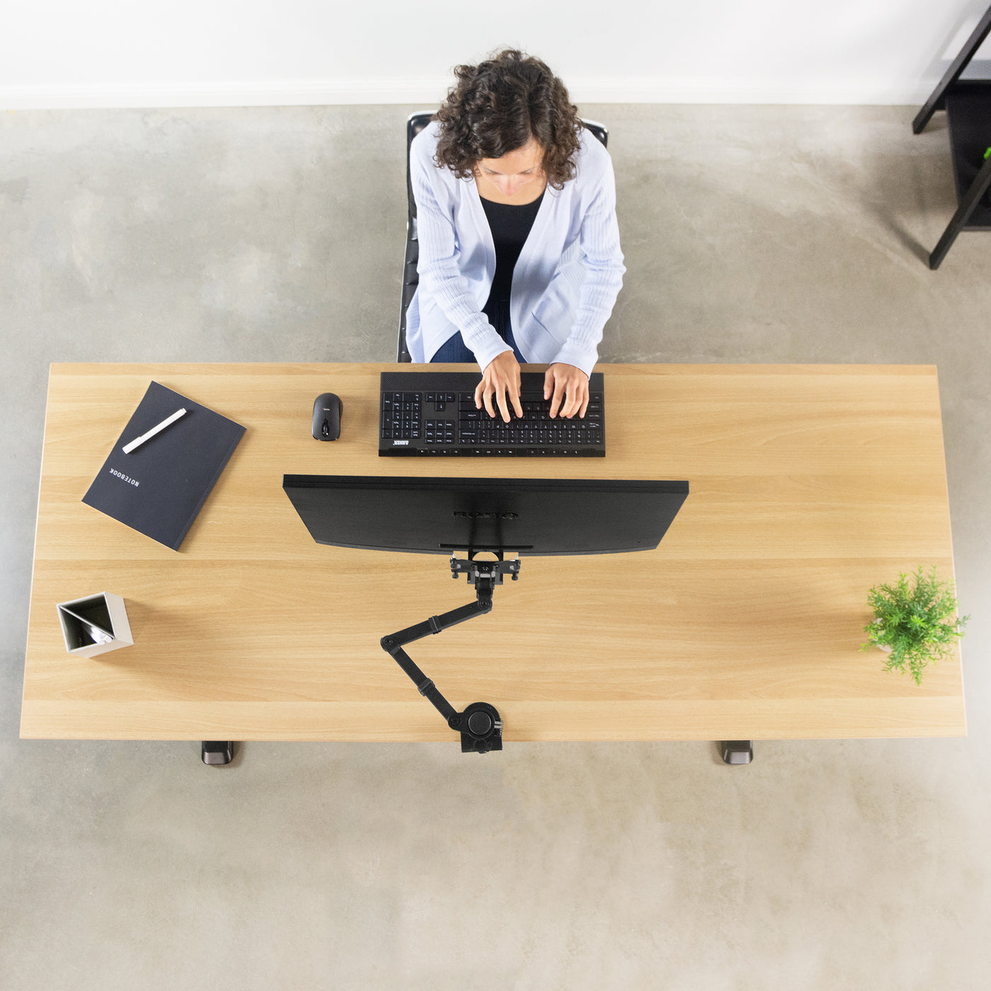 Ergonomic office set up with a woman working from a desk with a mounted BenQ monitor supported by a mount and VESA plate adapter bracket.