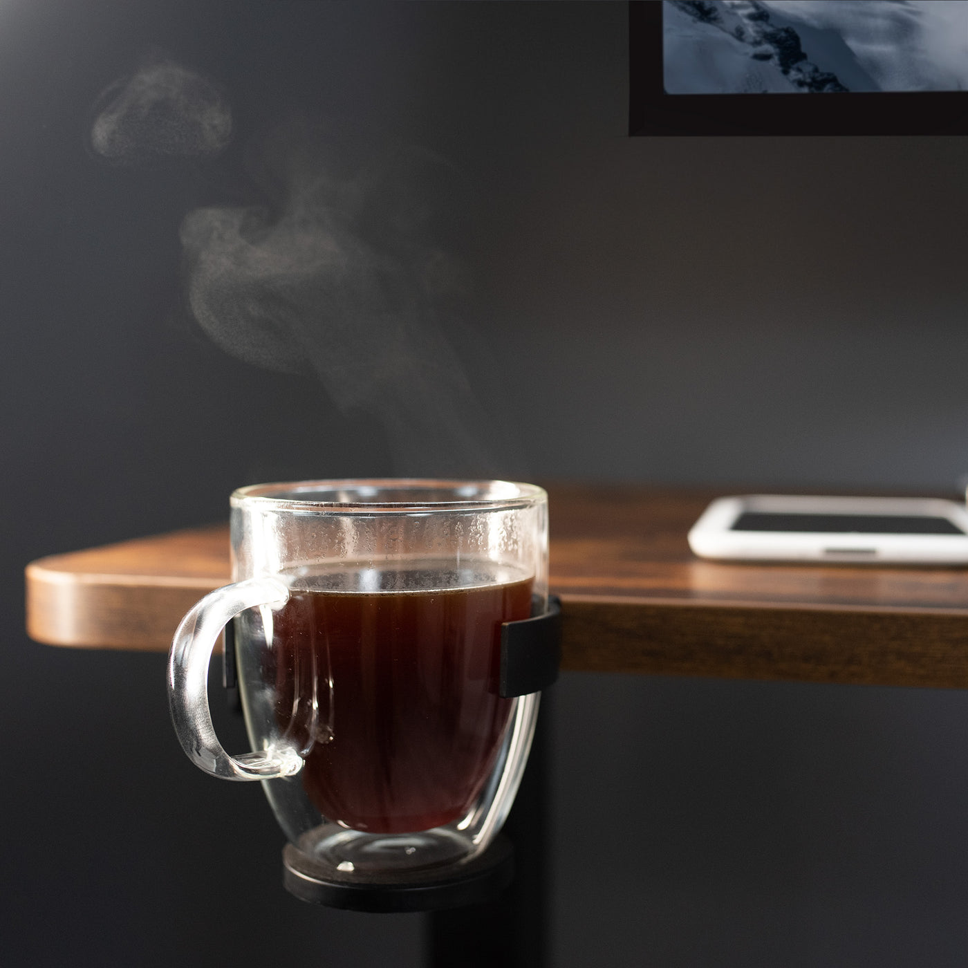 The side of the desk cup holder securely holds a hot cup of steaming coffee.