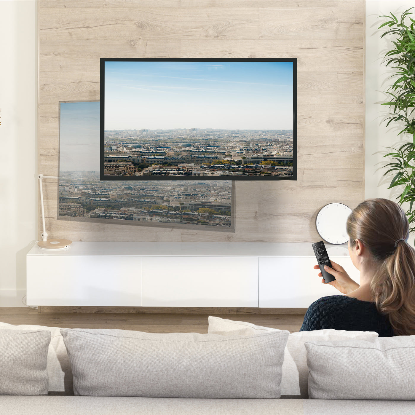 TV mounted in a living room setting adjusted to angle with remote control. 