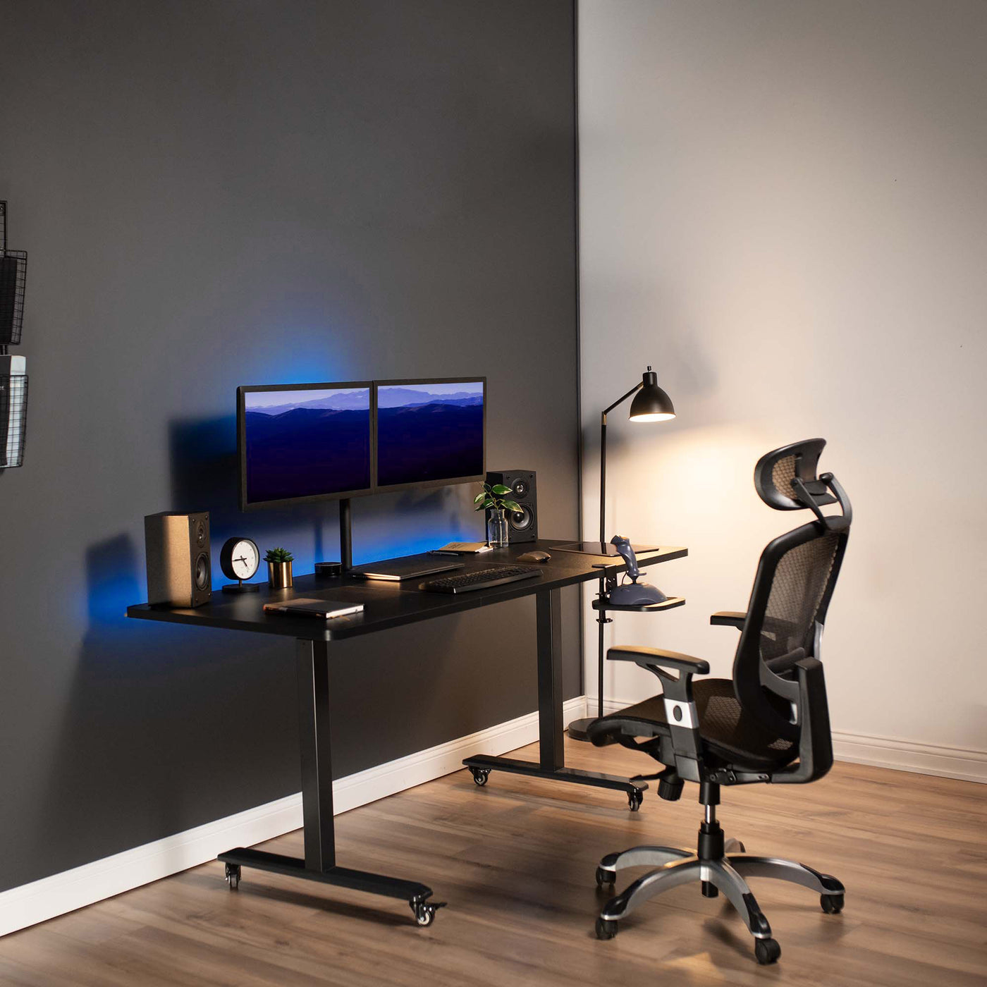 Modern office workspace with furnished sit-to-stand electric desk and under-desk mount keyboard and mouse tray.